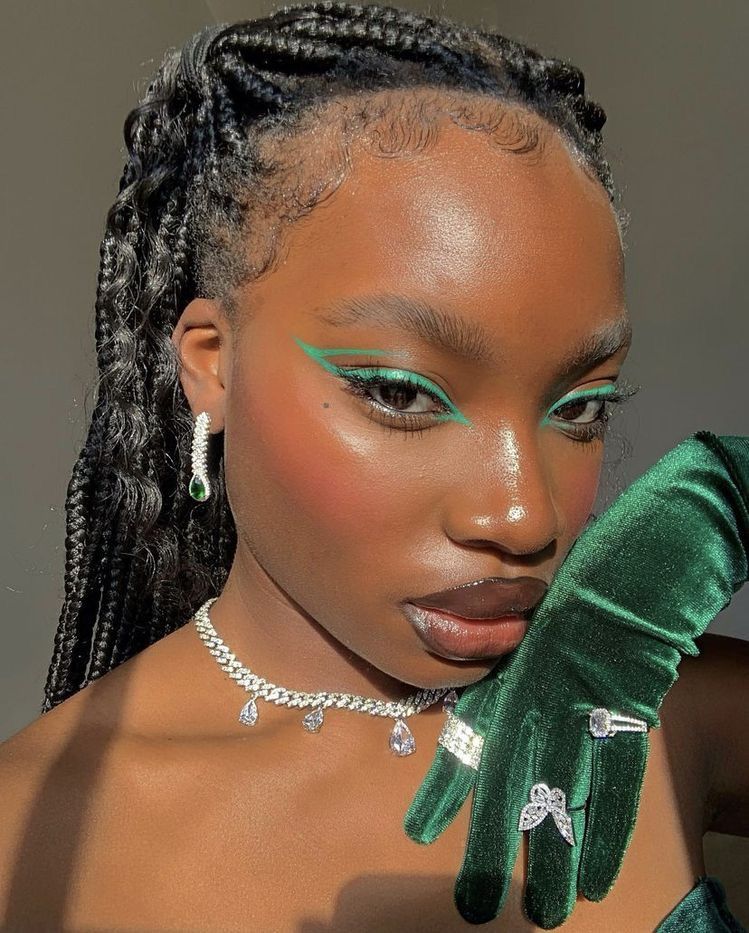 Mulher negra com maquiagem para a copa e delineado verde gráfico.