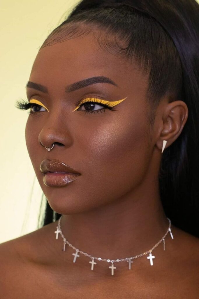Mulher negra com maquiagem para a copa e delineado amarelo gráfico.