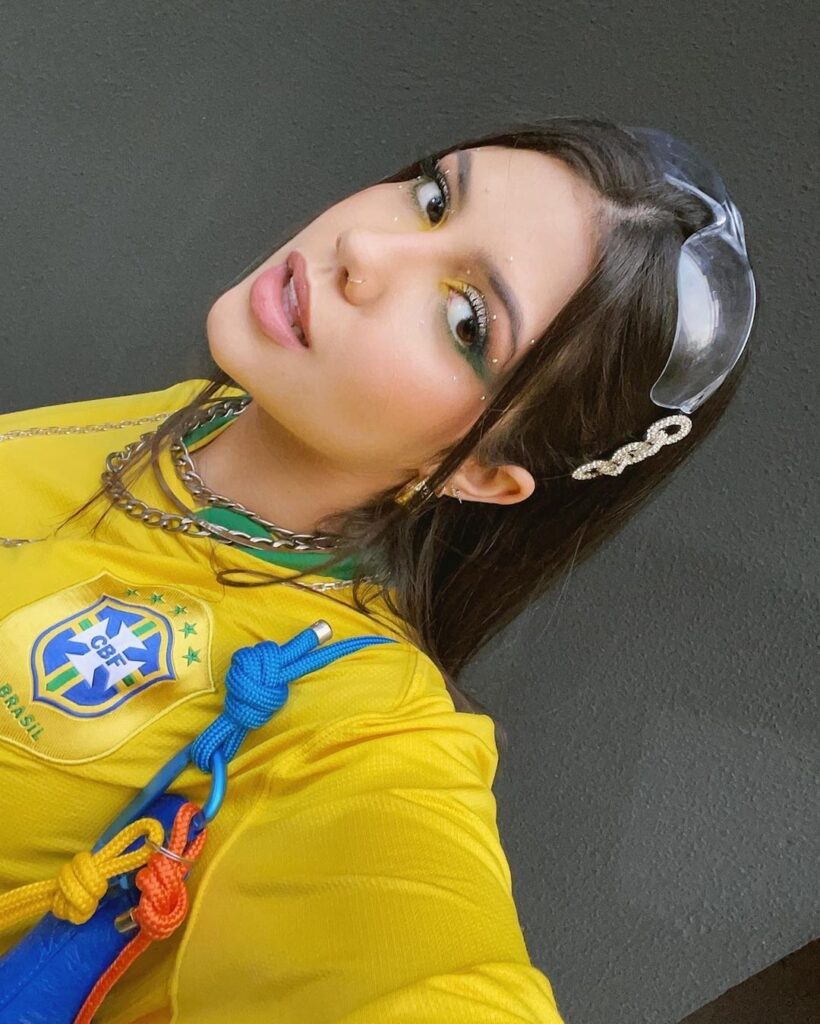 Mulher branca com cabelo castanho com maquiagem para a copa e delineado verde.