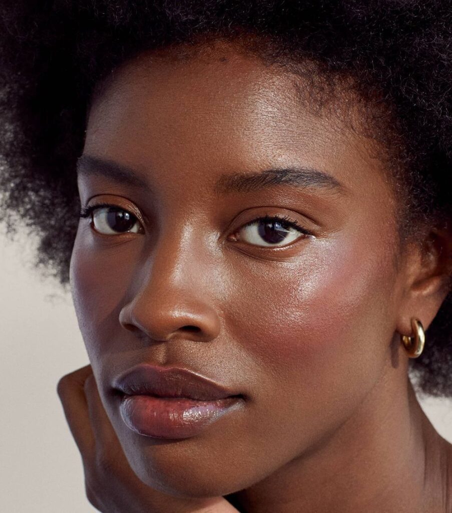 Mulher negra séria com maquiagem para pele negra suave.