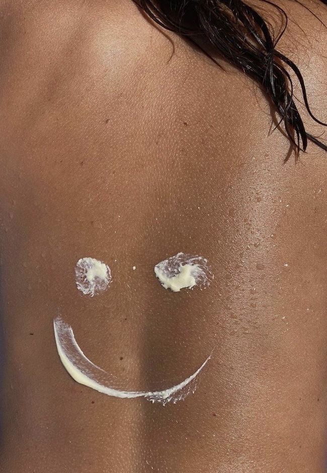 Costas de uma mulher com hidratante formando um sorriso representando os cuidados com a pele no frio.